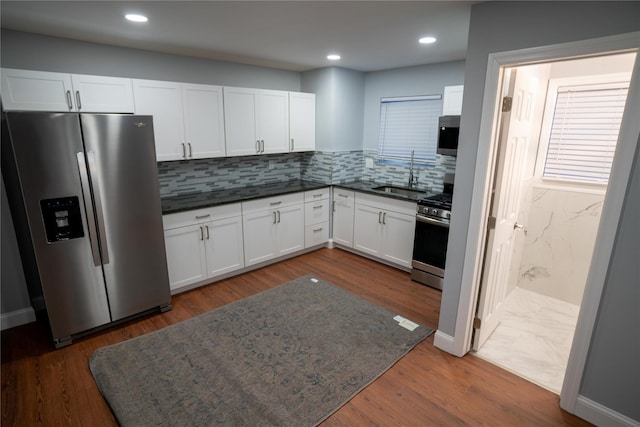 kitchen with sink, tasteful backsplash, dark hardwood / wood-style floors, white cabinets, and appliances with stainless steel finishes