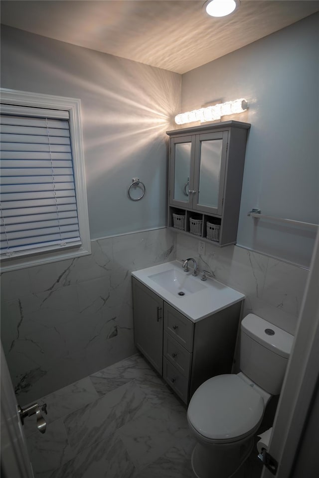 bathroom with vanity, toilet, and tile walls