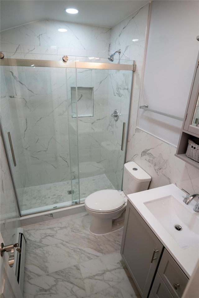 bathroom featuring walk in shower, vanity, toilet, and tile walls