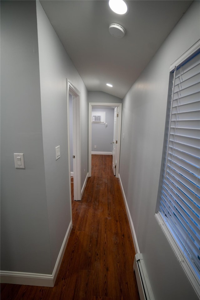 hallway with dark hardwood / wood-style flooring, vaulted ceiling, and a baseboard heating unit