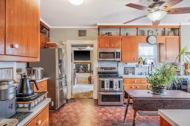 kitchen featuring stainless steel appliances, crown molding, ceiling fan, a wood stove, and sink