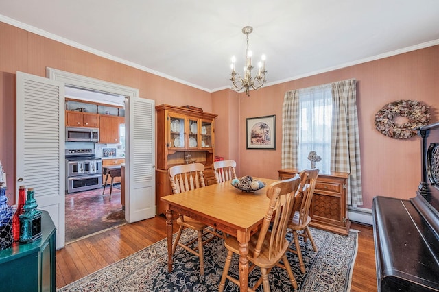 dining room featuring hardwood / wood-style flooring, an inviting chandelier, crown molding, and baseboard heating