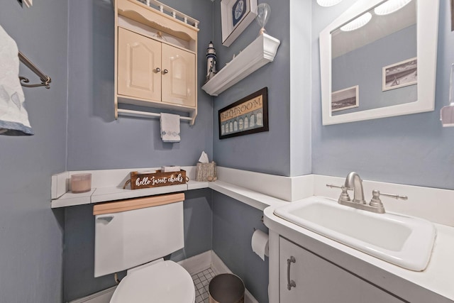 bathroom with toilet, vanity, and tile patterned floors