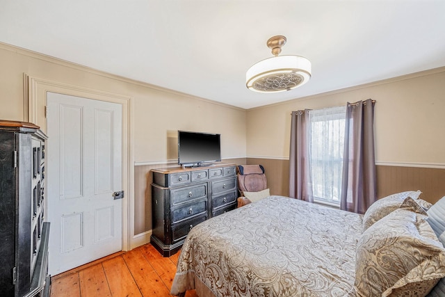 bedroom featuring light wood-type flooring, wooden walls, and crown molding