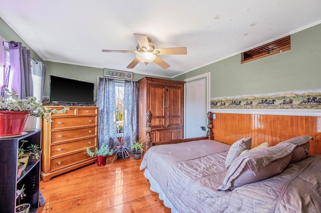 bedroom featuring ceiling fan, crown molding, wood-type flooring, and multiple windows