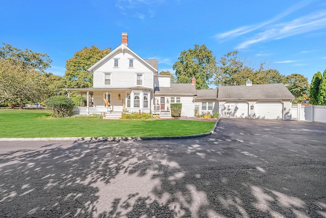 view of front of home featuring covered porch, a front lawn, and a garage