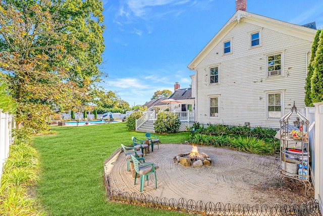 back of house with a yard, a fenced in pool, an outdoor fire pit, and a patio