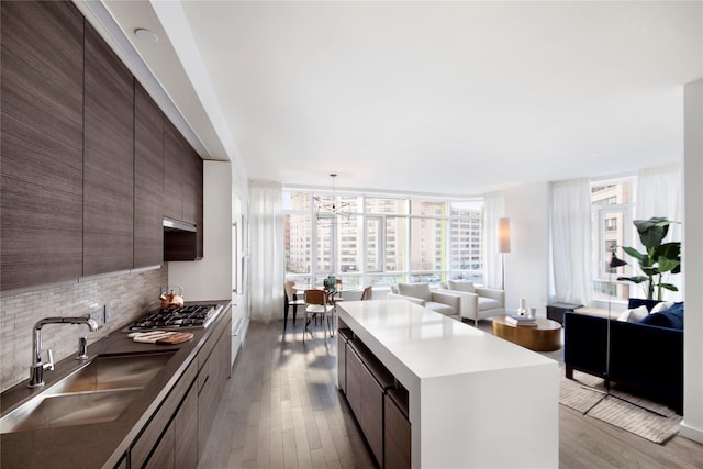 kitchen featuring a center island, expansive windows, sink, tasteful backsplash, and stainless steel gas cooktop