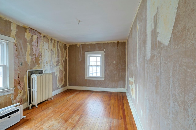 empty room featuring light wood-type flooring and radiator heating unit