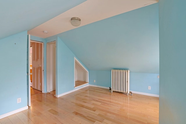 bonus room featuring radiator, lofted ceiling, and light wood-type flooring