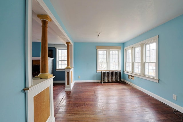 unfurnished living room featuring radiator heating unit, ornate columns, and hardwood / wood-style floors