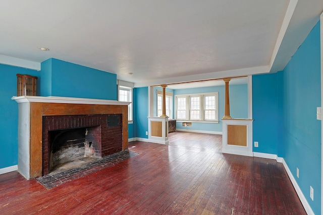 unfurnished living room featuring a fireplace, hardwood / wood-style flooring, and ornate columns