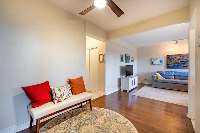 living room featuring beamed ceiling, ceiling fan, and dark wood-type flooring