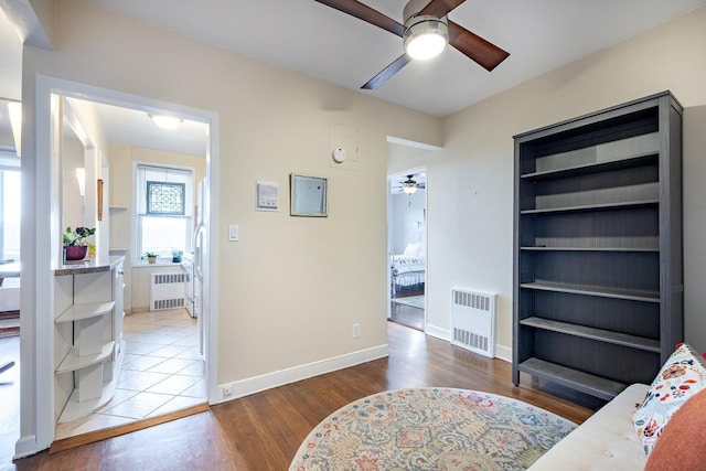 bedroom with radiator heating unit, ceiling fan, and wood-type flooring