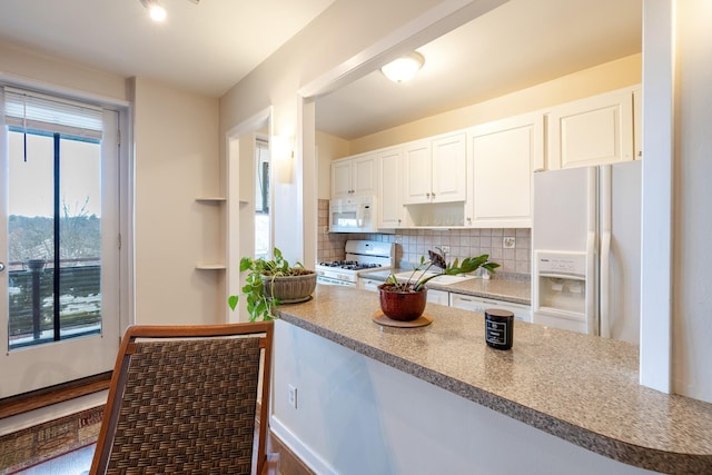 kitchen featuring white appliances, tasteful backsplash, and white cabinetry