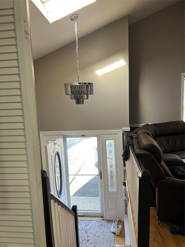 entrance foyer with vaulted ceiling with skylight, hardwood / wood-style floors, and a notable chandelier