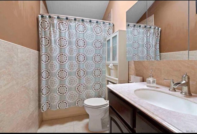 bathroom with tile patterned flooring, vanity, tile walls, and toilet