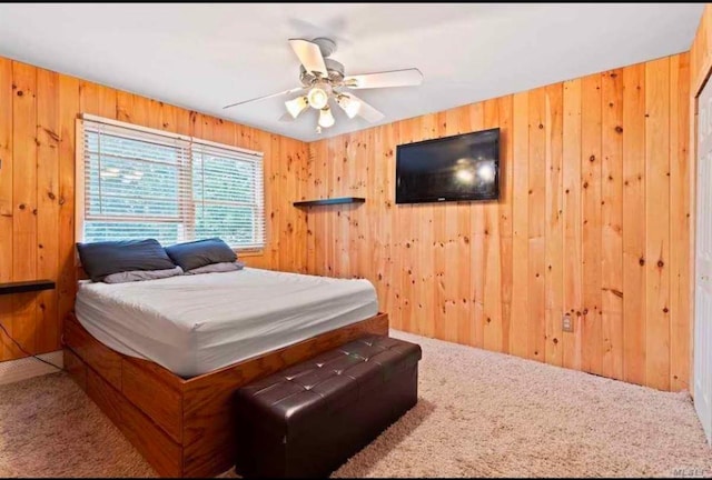 carpeted bedroom featuring ceiling fan and wooden walls