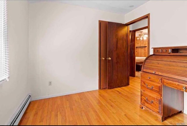 unfurnished office with a baseboard radiator, ceiling fan, and light hardwood / wood-style floors