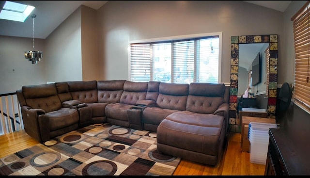 living room featuring an inviting chandelier, vaulted ceiling with skylight, and light hardwood / wood-style floors