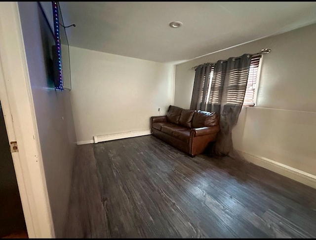 living area featuring a baseboard heating unit and dark wood-type flooring