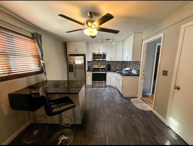 kitchen featuring appliances with stainless steel finishes, a kitchen breakfast bar, kitchen peninsula, decorative backsplash, and white cabinets