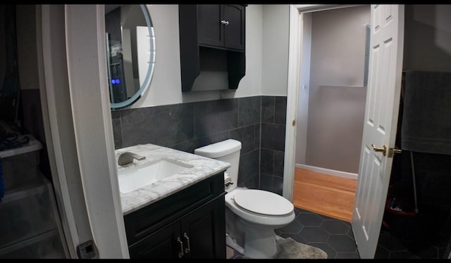 bathroom featuring vanity, toilet, tile patterned flooring, and tile walls