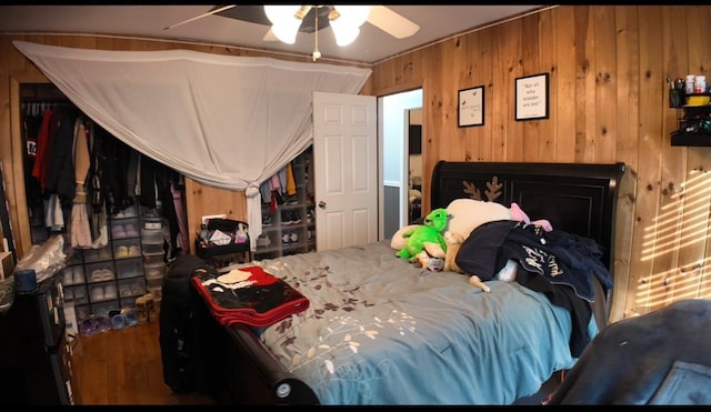 bedroom with ceiling fan, hardwood / wood-style floors, and wood walls