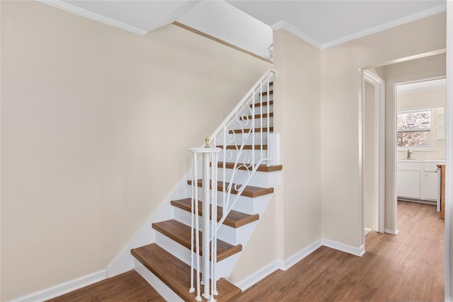 stairway featuring crown molding, hardwood / wood-style floors, and sink