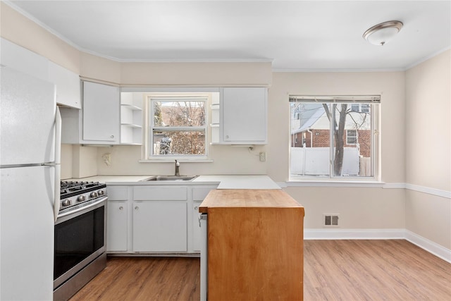 kitchen featuring white fridge, gas range, and white cabinets