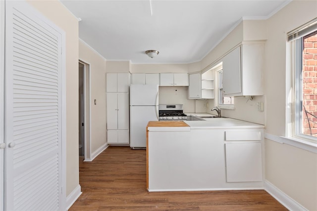 kitchen featuring dark hardwood / wood-style floors, white fridge, stainless steel gas range oven, sink, and white cabinets