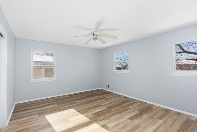 spare room featuring ceiling fan, a healthy amount of sunlight, and light hardwood / wood-style flooring