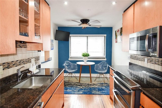 kitchen with light hardwood / wood-style floors, dark stone countertops, sink, and tasteful backsplash