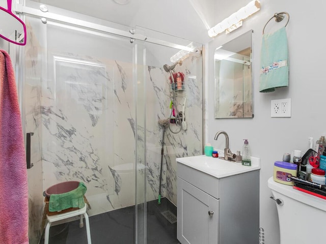 bathroom featuring vanity, a shower with shower door, and toilet