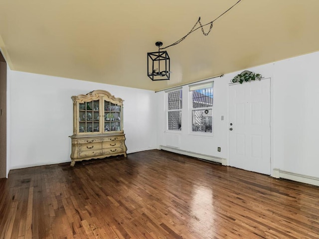 unfurnished dining area featuring a chandelier, dark hardwood / wood-style floors, and baseboard heating