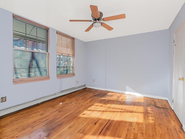 empty room with ceiling fan, wood-type flooring, and a baseboard heating unit