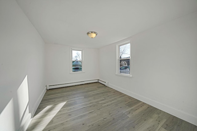 unfurnished room with a healthy amount of sunlight, baseboard heating, and light hardwood / wood-style flooring