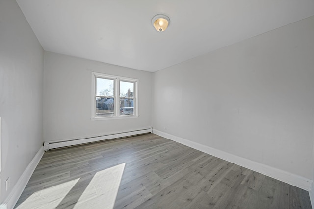 empty room featuring a baseboard radiator and light hardwood / wood-style floors