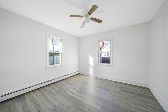 unfurnished room featuring hardwood / wood-style floors, ceiling fan, a healthy amount of sunlight, and baseboard heating