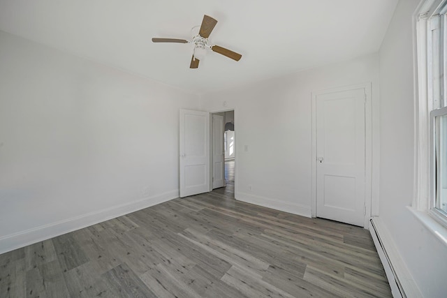 unfurnished bedroom with wood-type flooring, baseboard heating, and ceiling fan