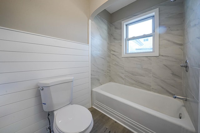 bathroom with tiled shower / bath combo, toilet, and wood-type flooring