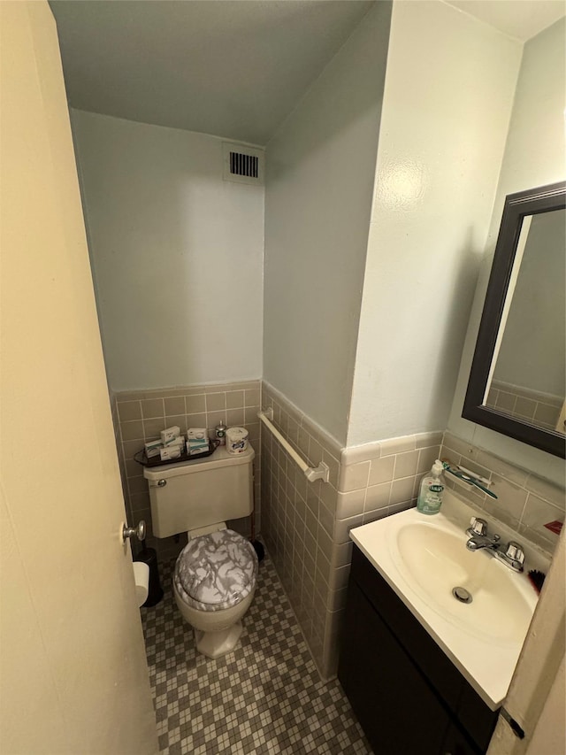 bathroom with tile patterned flooring, vanity, tile walls, and toilet