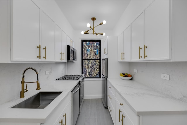 kitchen featuring white cabinets, light stone counters, sink, and appliances with stainless steel finishes