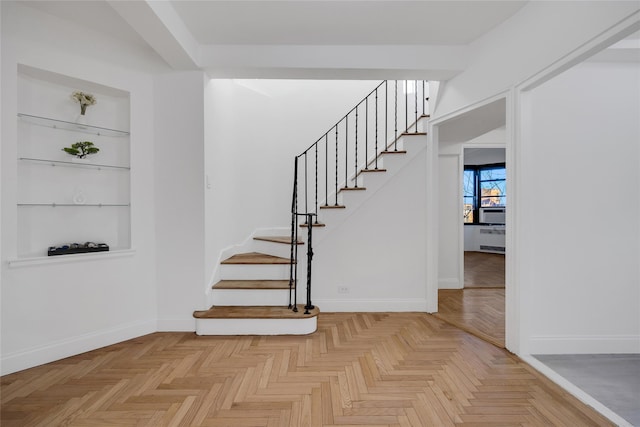 staircase featuring built in features and parquet flooring