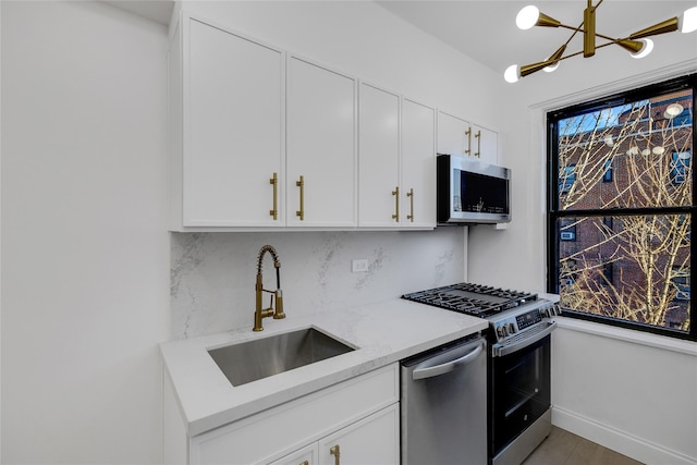 kitchen featuring light stone countertops, white cabinetry, sink, stainless steel appliances, and decorative backsplash