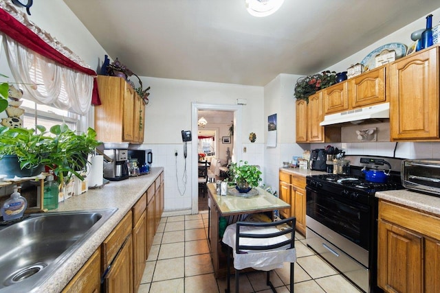 kitchen featuring a wealth of natural light, stove, sink, and light tile patterned flooring