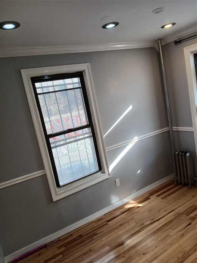 interior space featuring crown molding, radiator heating unit, and hardwood / wood-style flooring