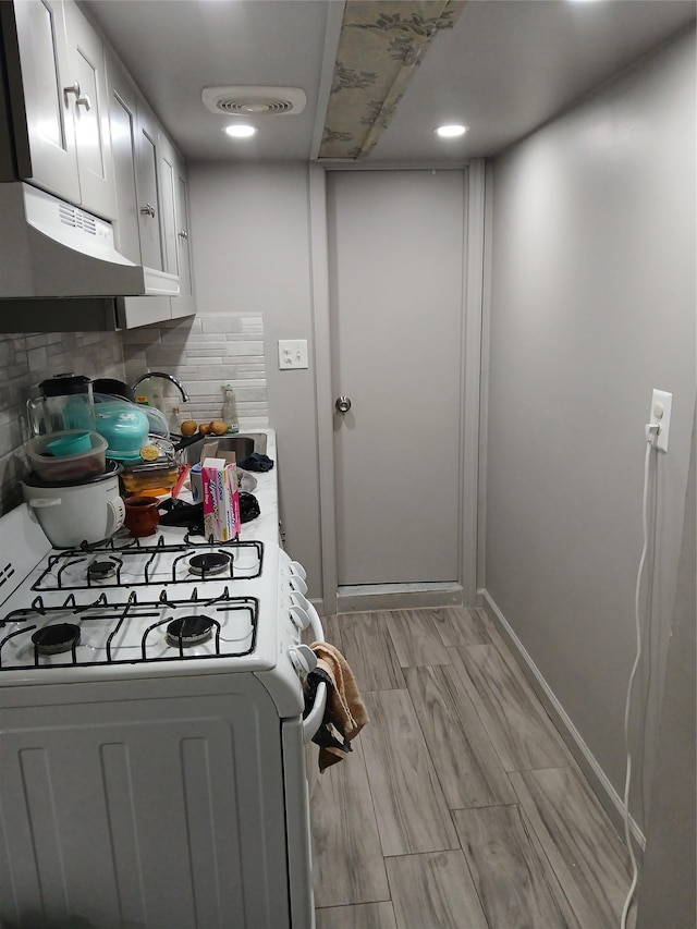 kitchen featuring white cabinets, decorative backsplash, white gas range, and sink