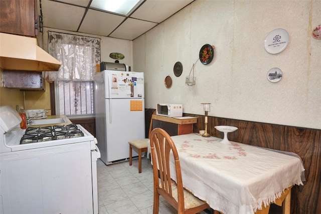 dining space with wood walls and a drop ceiling