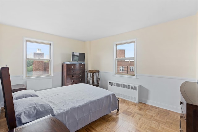 bedroom featuring radiator and light parquet flooring